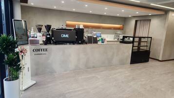 Een moderne koffiecorner met een digitaal scherm, koffieapparaten en een menubord.