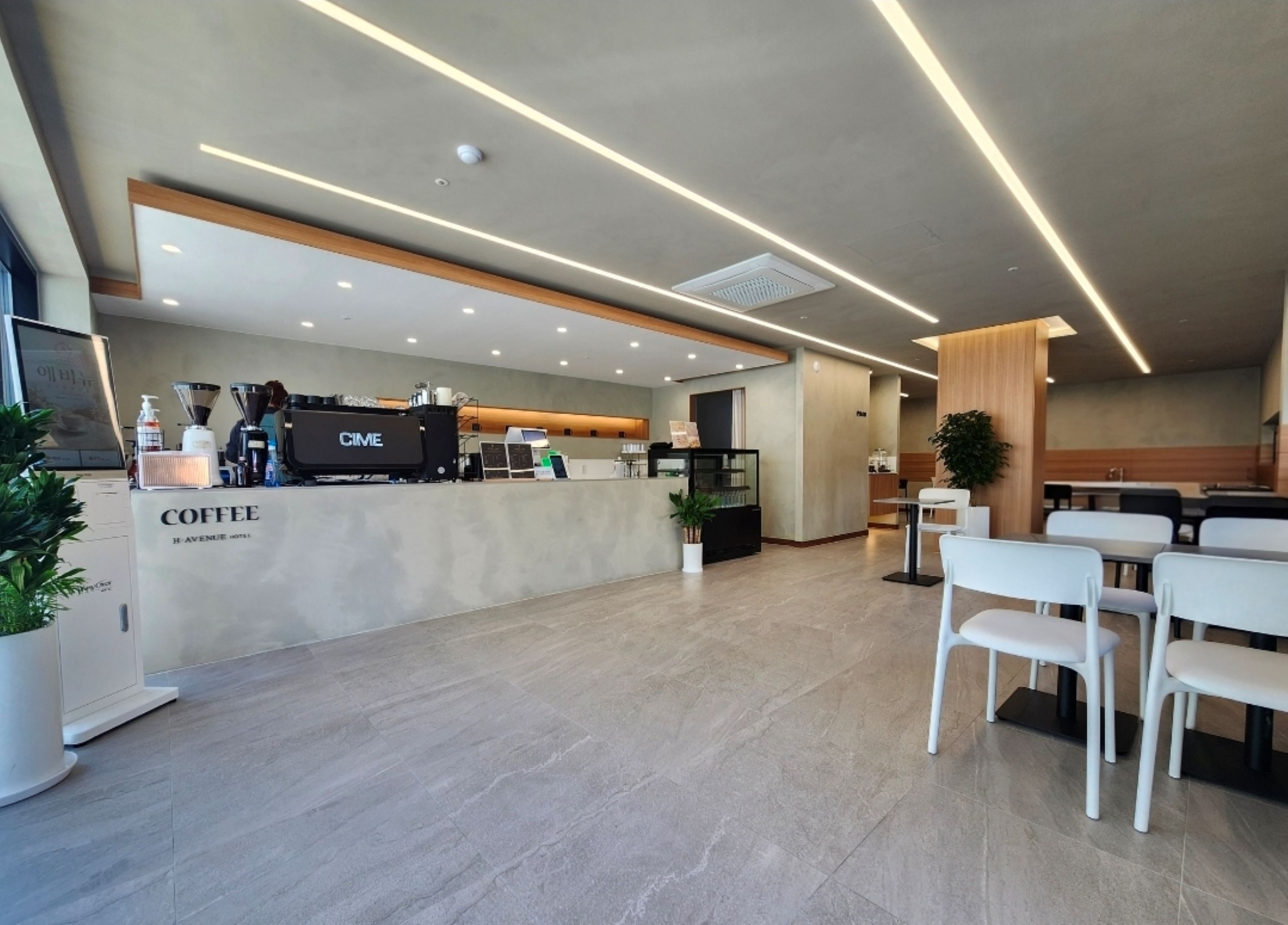 Ein modernes Café mit einer Theke, Sitzbereich und einem klaren, zeitgemäßen Design.