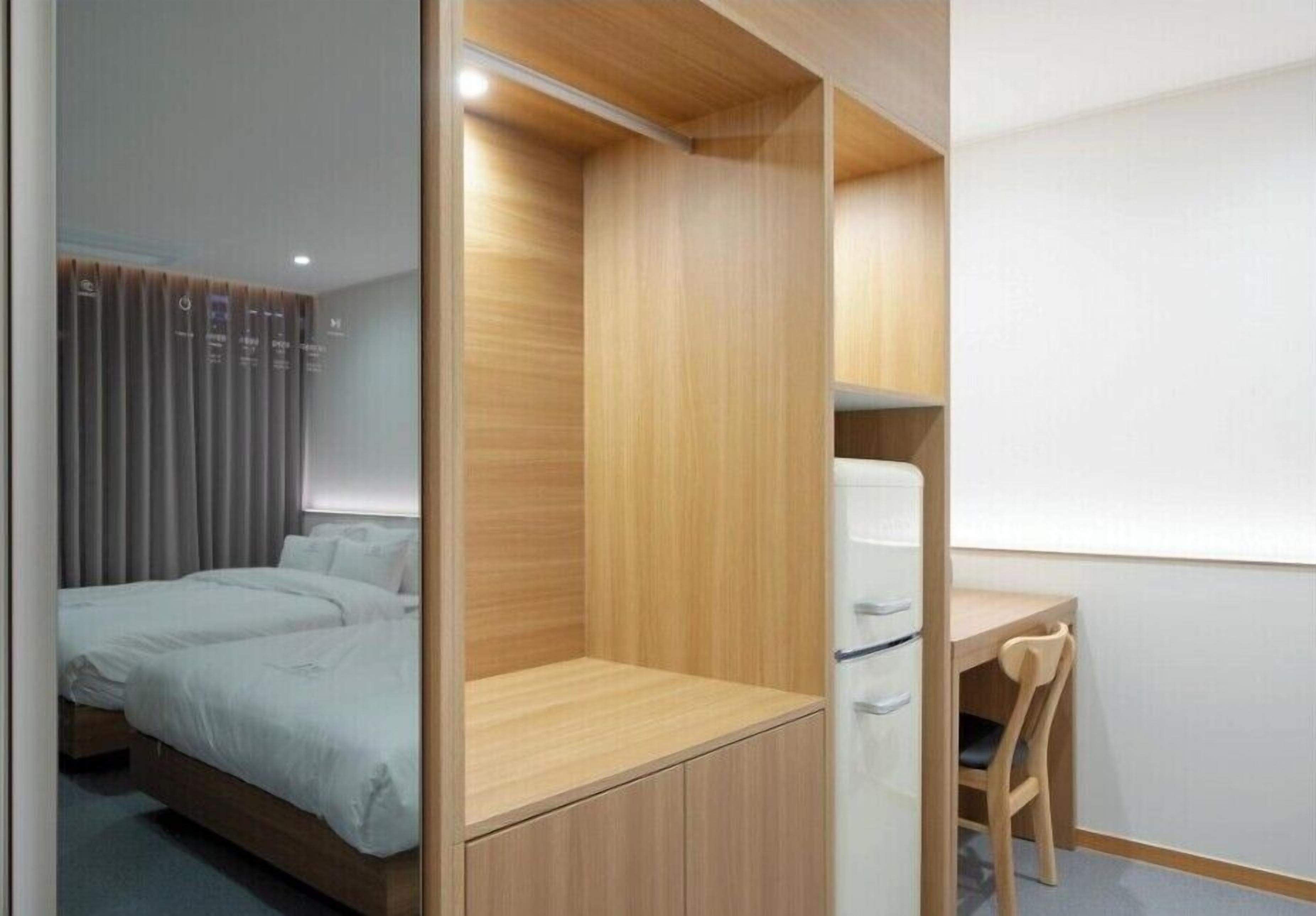 A bedroom with a bed, a desk, and a chair.
