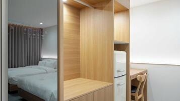 A bedroom with a bed, a desk, and a chair.