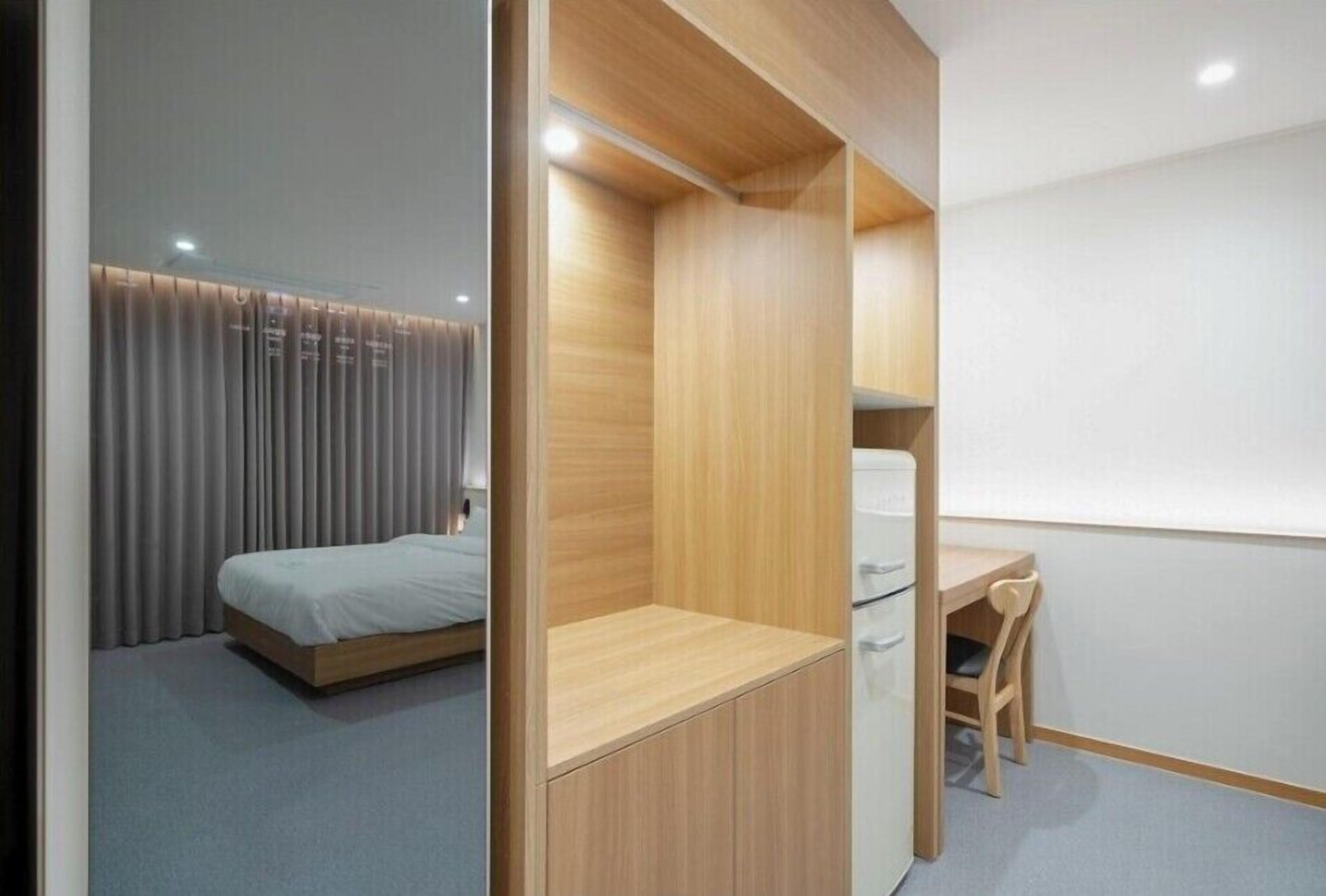 Een kleine slaapkamer met een bed, een bureau en een stoel.