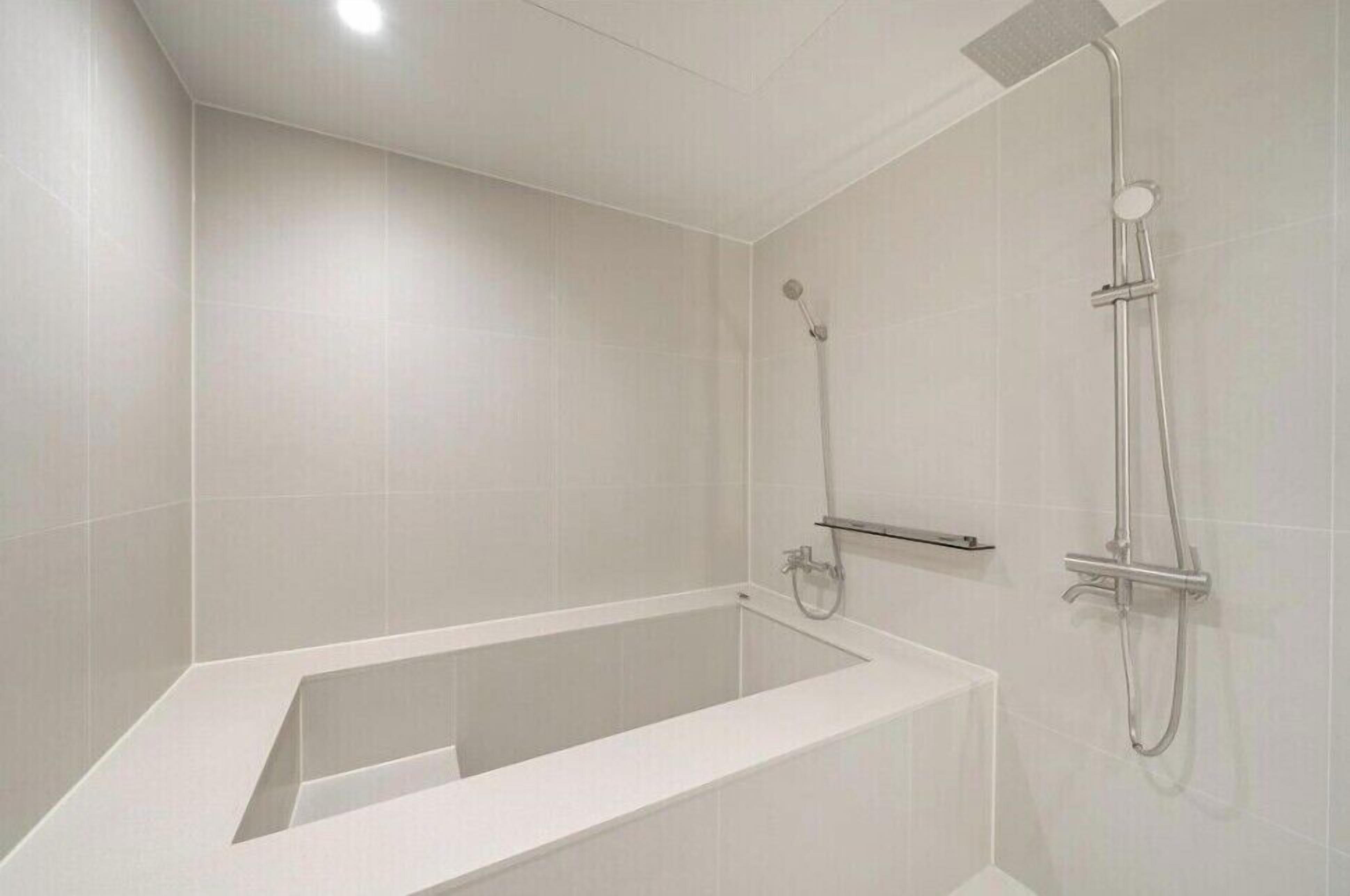 Ein modernes Badezimmer mit einer freistehenden Badewanne, einer Handbrause und einer Wandbrause.