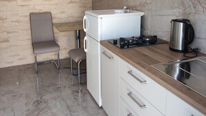 Una cocina moderna con encimera de mármol, estufa integrada, refrigerador blanco y una silla gris.