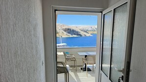 Un balcone con tavolo e sedie, affacciato su un corpo d'acqua e delle colline.