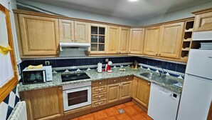 Una cucina con mobili in legno, un forno a microonde, un forno, un lavandino e un frigorifero.