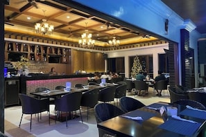 Un restaurante con barra, mesas y sillas.