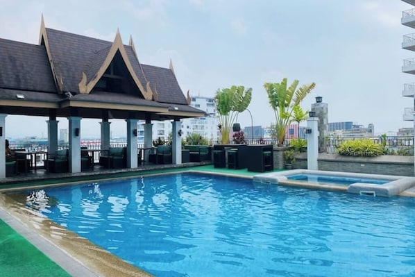 Ein Pool auf dem Dach mit einer überdachten Sitzgelegenheit und Blick auf die Stadtlandschaft.
