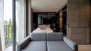 A modern hotel room with a large bed, a sofa, and a balcony with a view of greenery. - Seaphere residence by Prop Hopper (Sattahip)