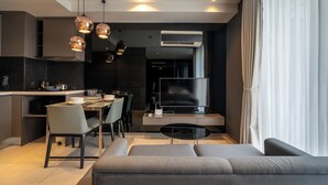 A modern living room with a sofa, a dining area with chairs and a table, and a kitchen with a TV and air conditioning unit. - Seaphere residence by Prop Hopper (Sattahip)