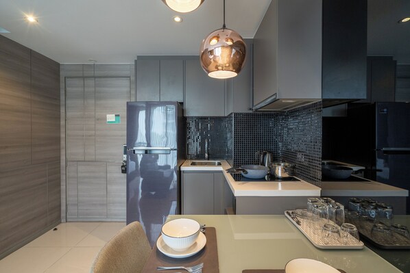 A modern kitchen with a stainless steel refrigerator, a sink, and a dining area with a table set for two.