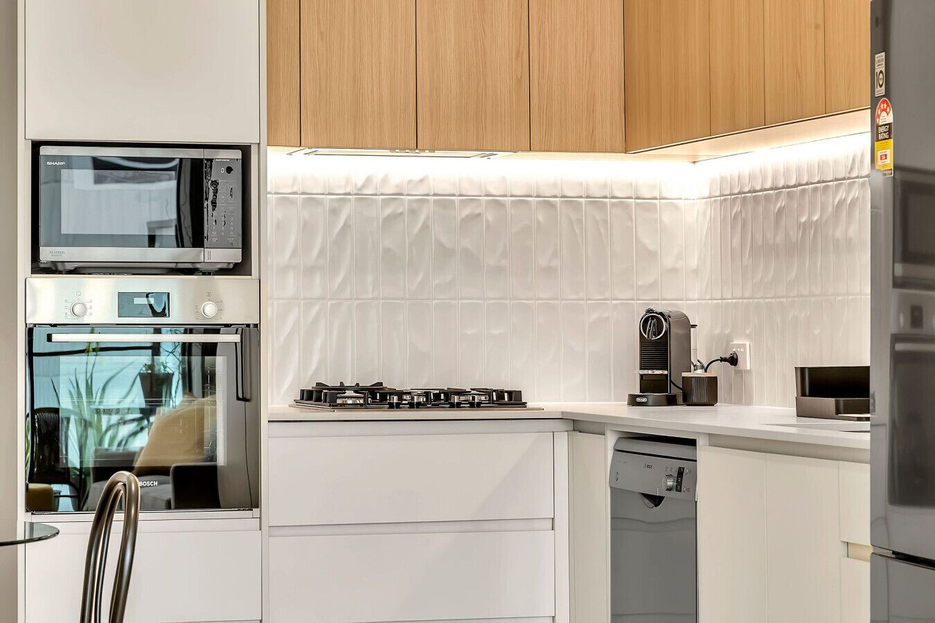 A modern kitchen with white cabinetry, a Bosch dishwasher, a gas stove, and a microwave.