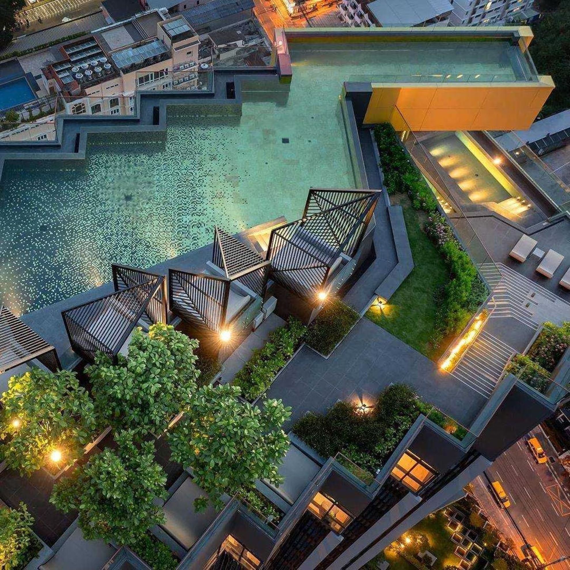 An aerial view of a hotel with a swimming pool, outdoor seating, and greenery.