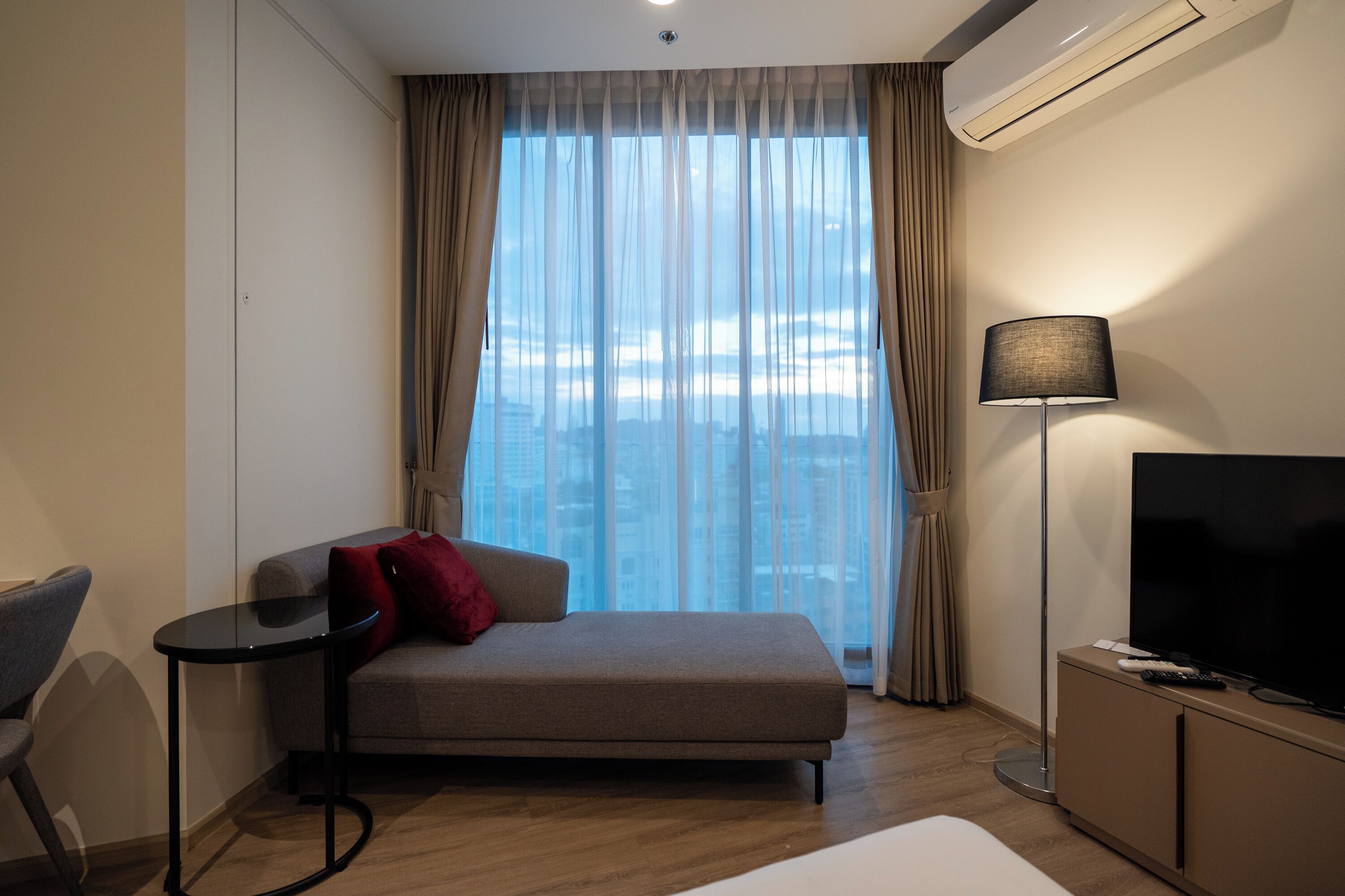 Ett hotellrum med en soffa, ett litet bord, en tv och en lampa.