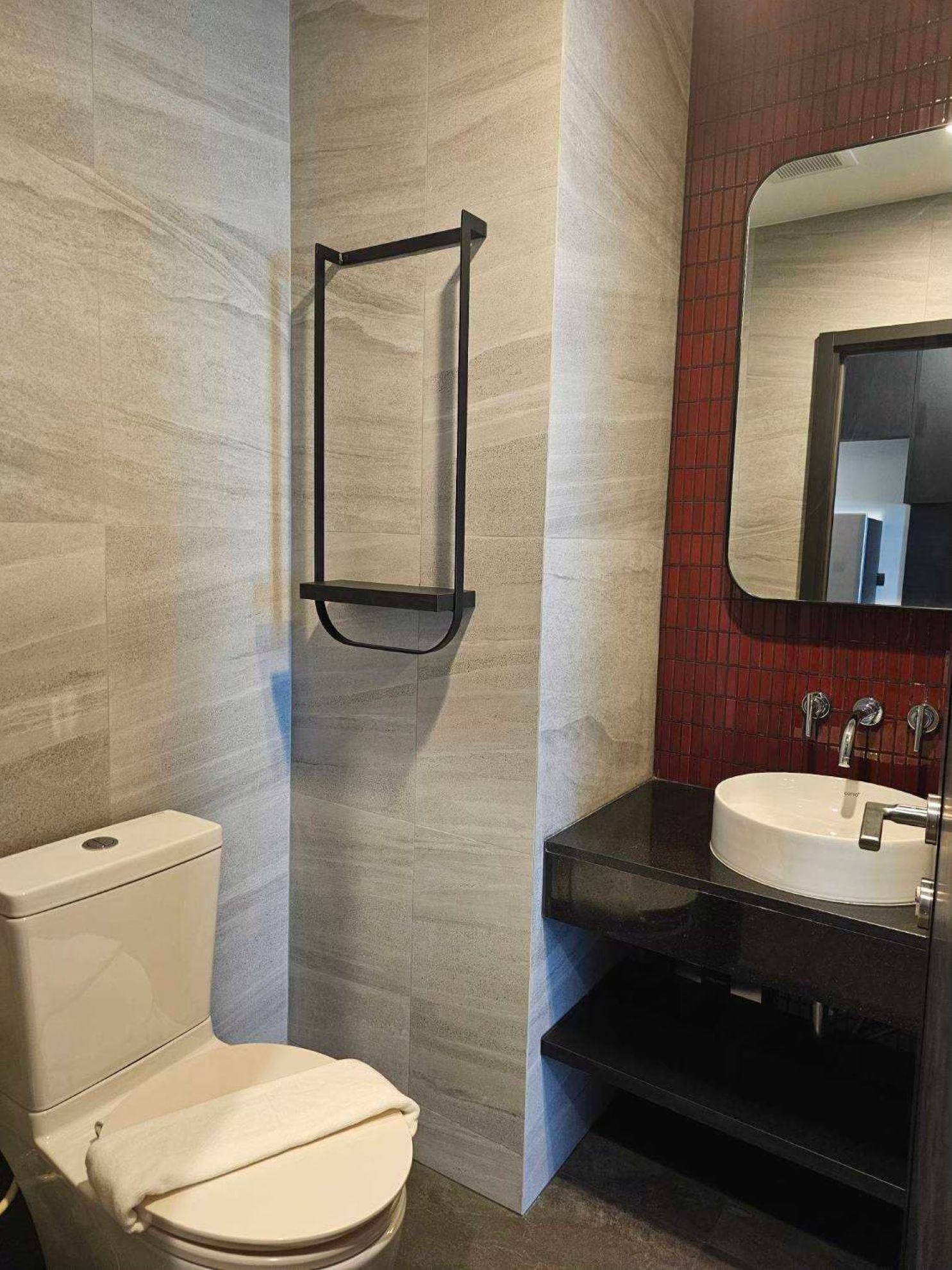 Ein modernes Badezimmer mit Toilette, Waschbecken und Spiegel.