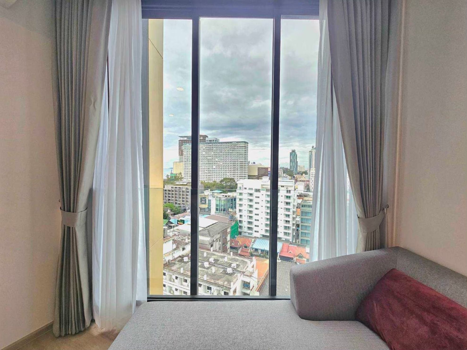 A room with a large window, a bed, and curtains.