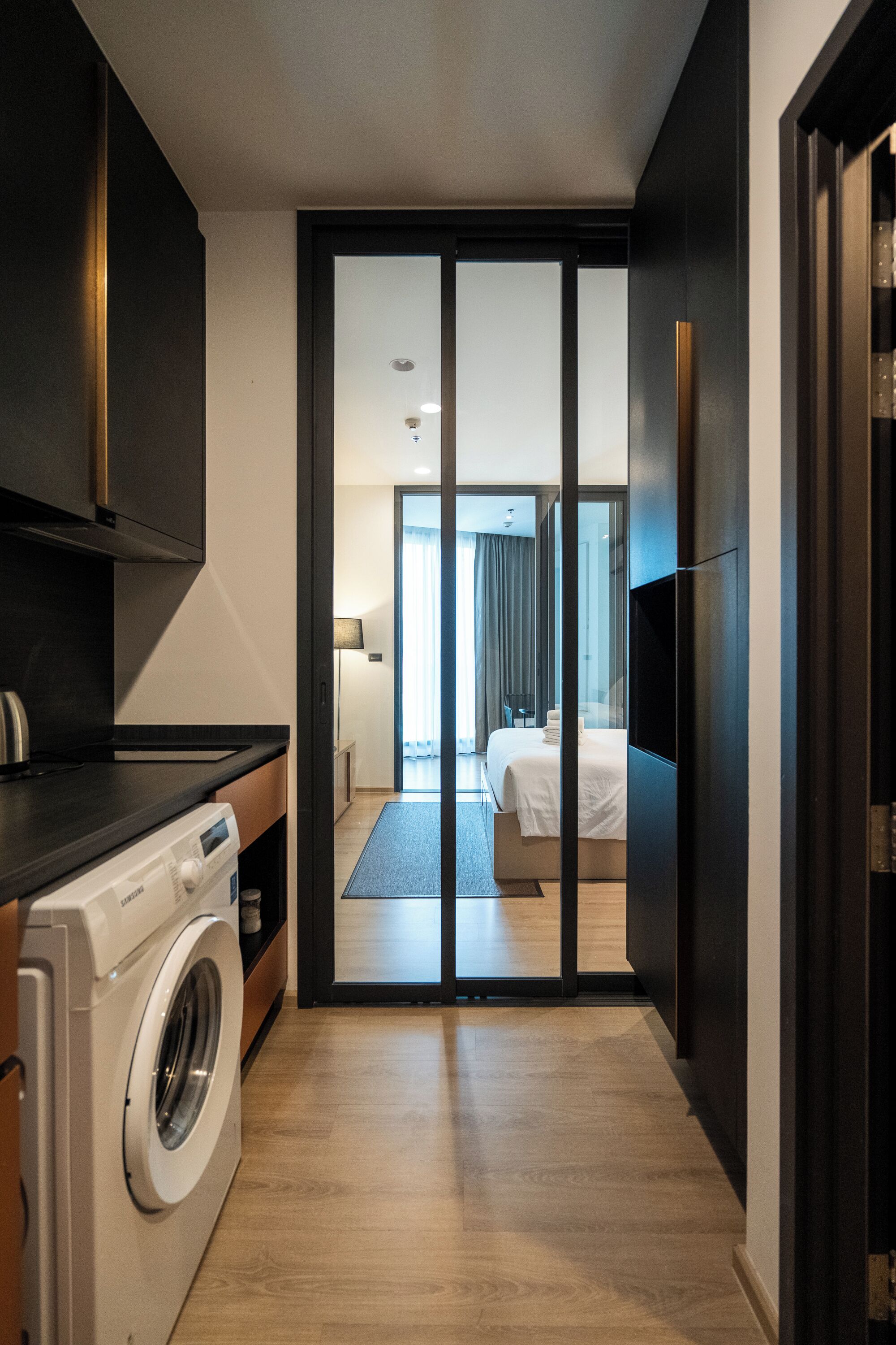 A modern hotel room with a large bed, a TV, and a washing machine in the corner.