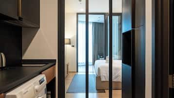 A modern hotel room with a large bed, a TV, and a washing machine in the corner.