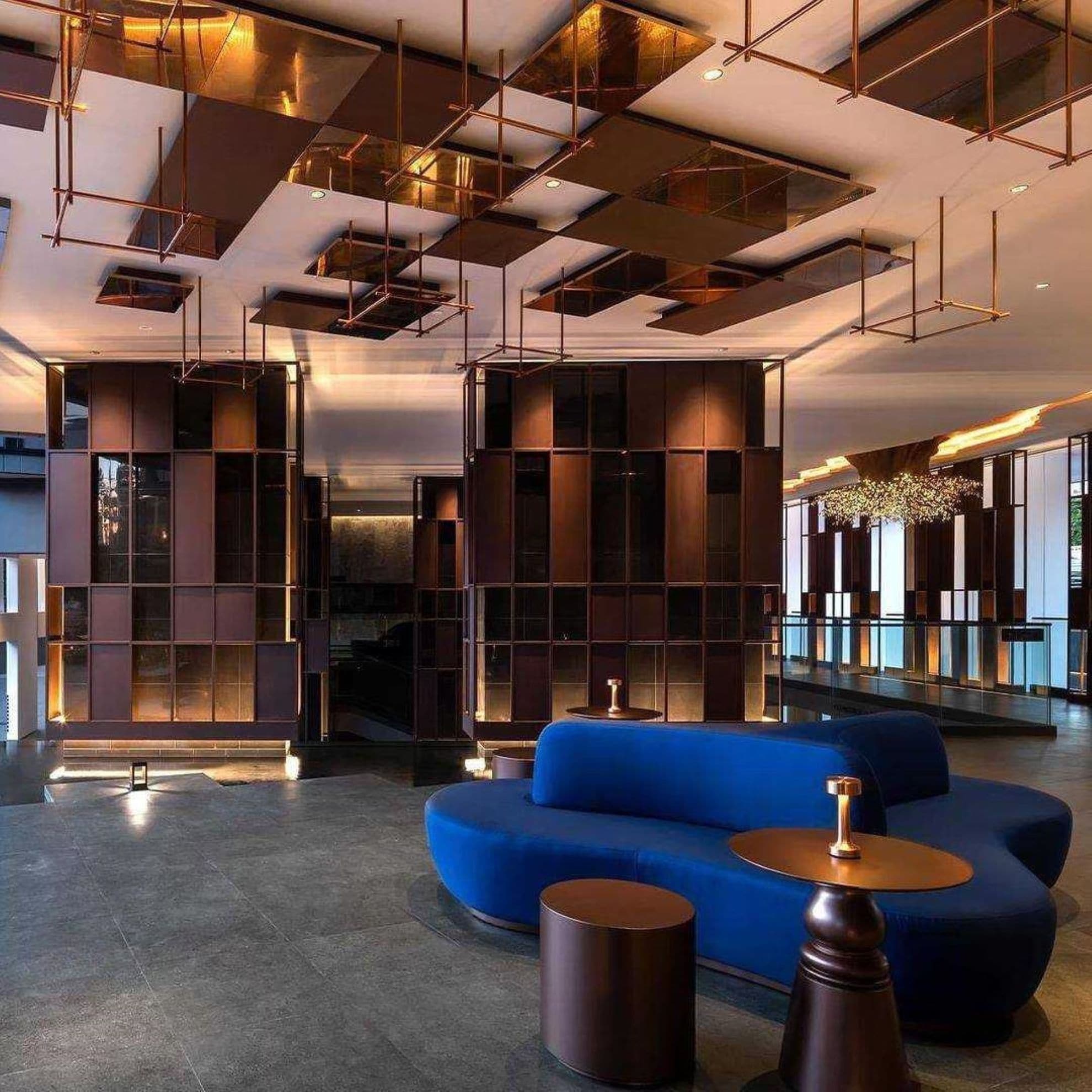 A modern lobby with a blue sofa, metal shelving, and a chandelier.