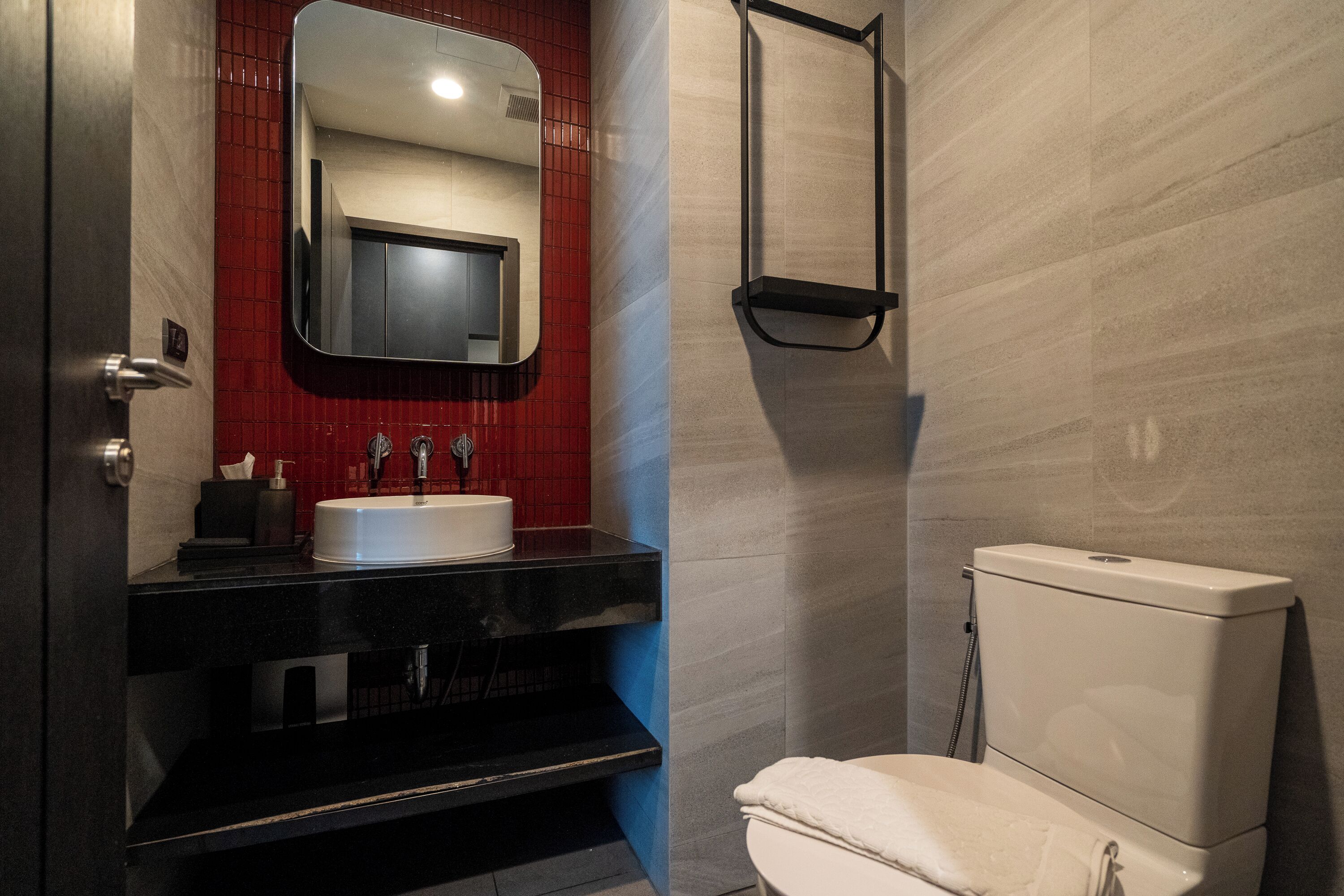 Un bany modern amb un tocador negre, un lavabo blanc i un vàter.