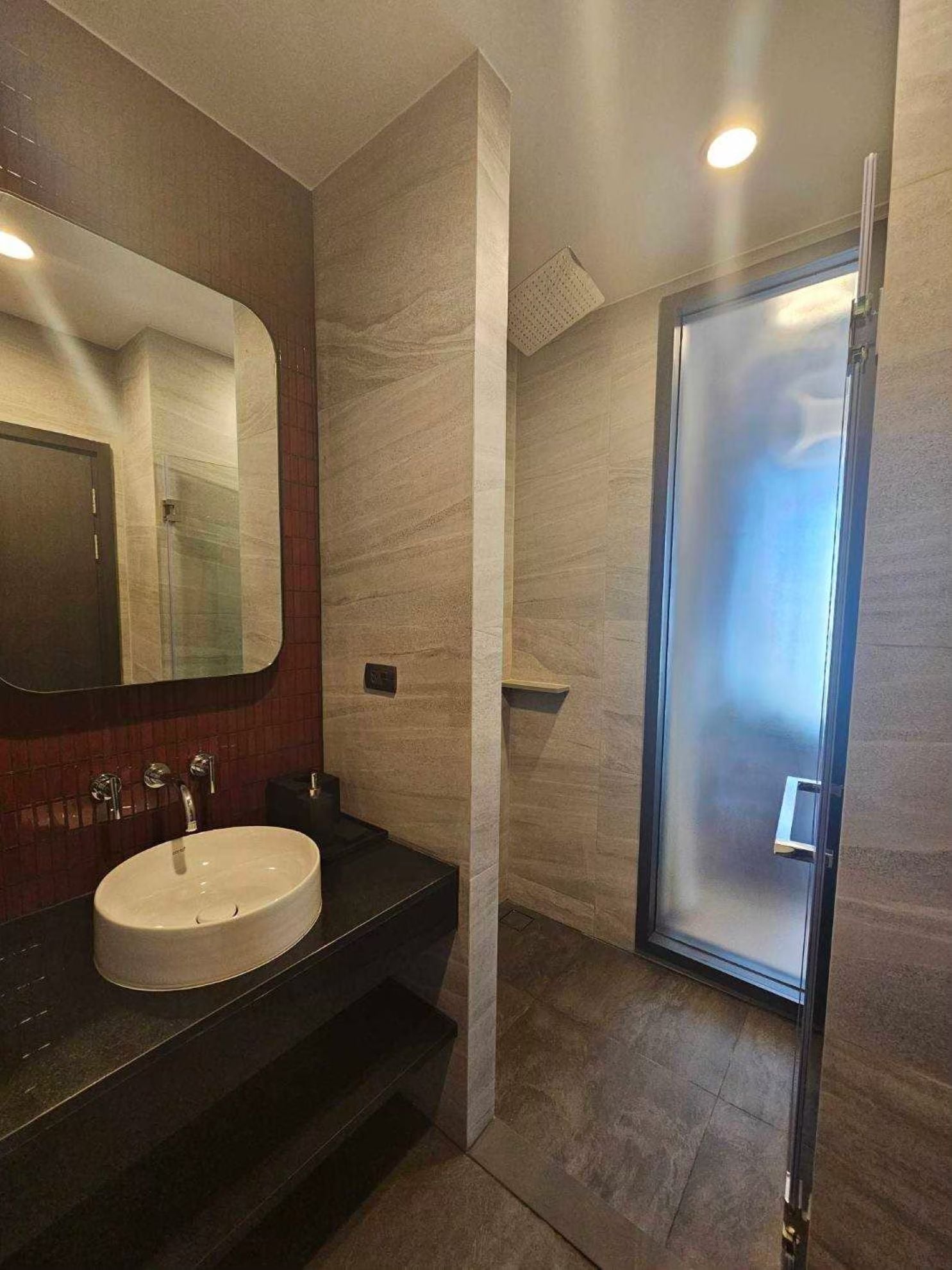 Ein modernes Badezimmer mit großem Spiegel, Waschbecken und einer Duschkabine aus Glas.