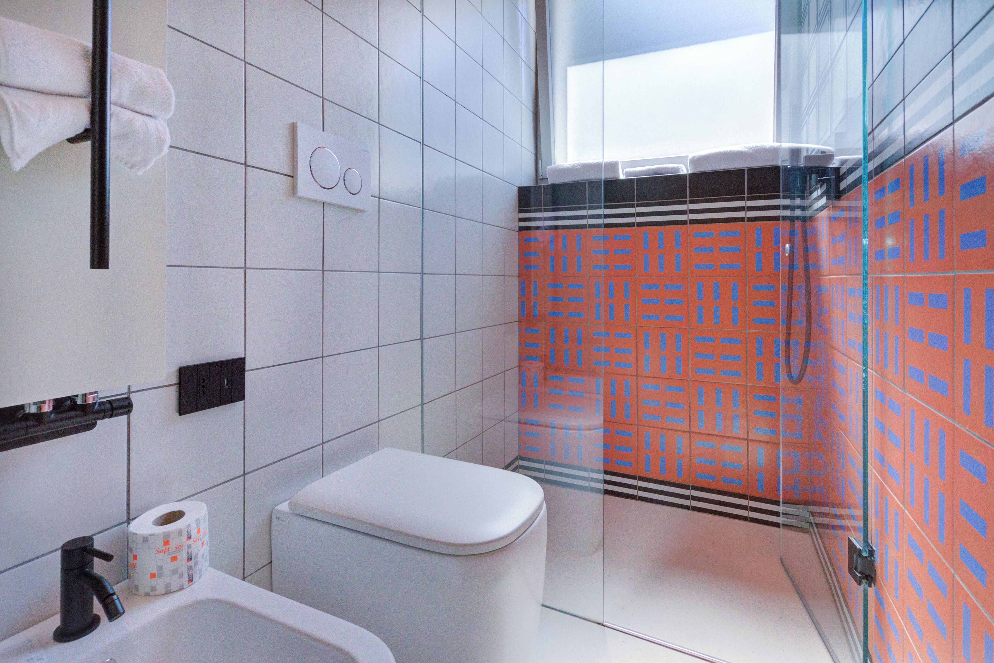 A bathroom with a toilet, sink, and a glass shower enclosure.