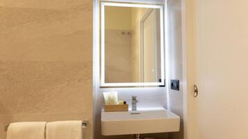 A bathroom with a white sink, a mirror with under-cabinet lighting, and a towel rack.