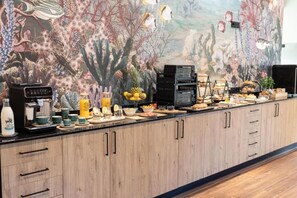 A buffet setup with various food items and beverages, a coffee machine, and a microwave.