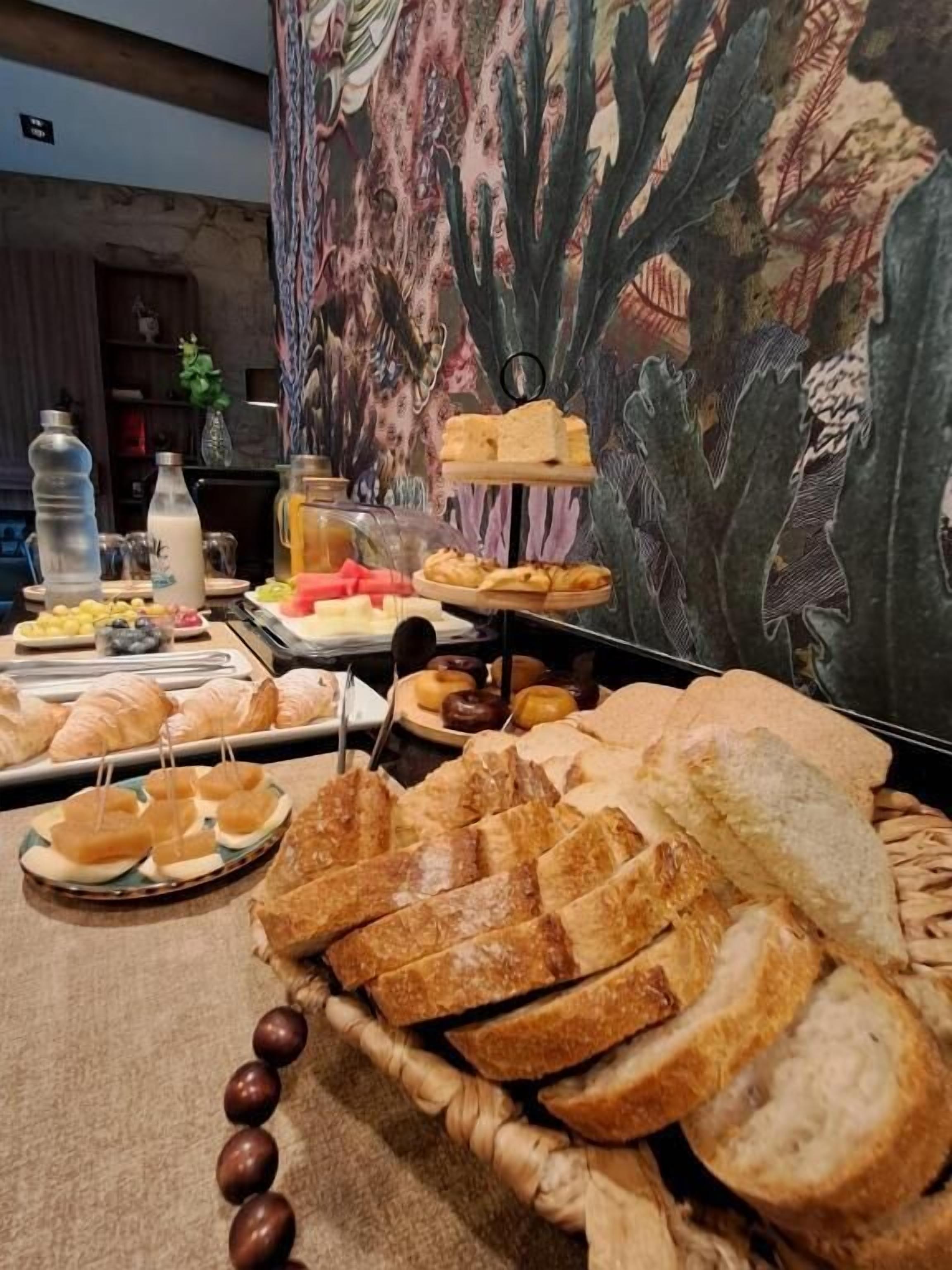 Taula de buffet amb diferents aliments, com ara pa, pastissos i fruita.