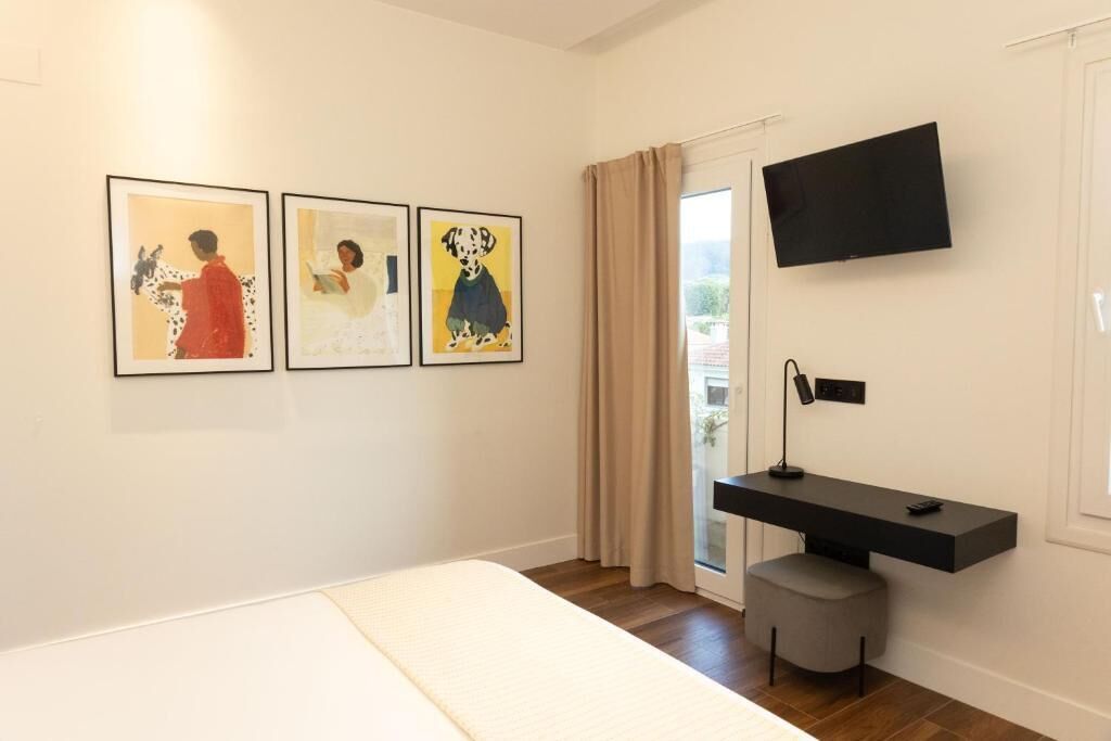 A modern bedroom with a bed, a mounted TV, and three framed artworks on the wall.