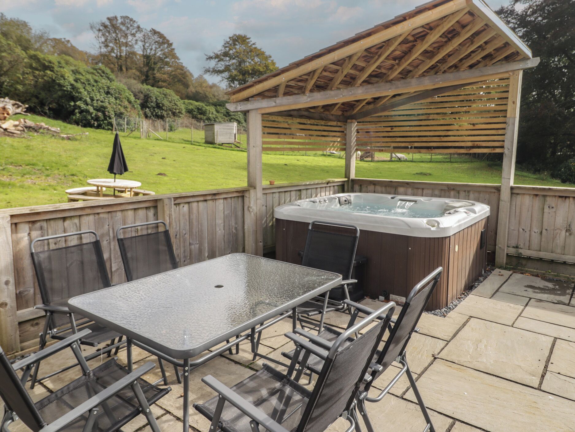 Ein Außenbereich mit Whirlpool, einer Holzpergola, einem Tisch und Stühlen.