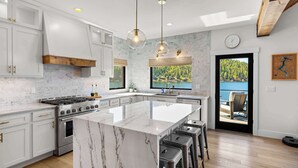 Una cocina moderna con encimeras de mármol, electrodomésticos de acero inoxidable y una isla grande con taburetes de bar.