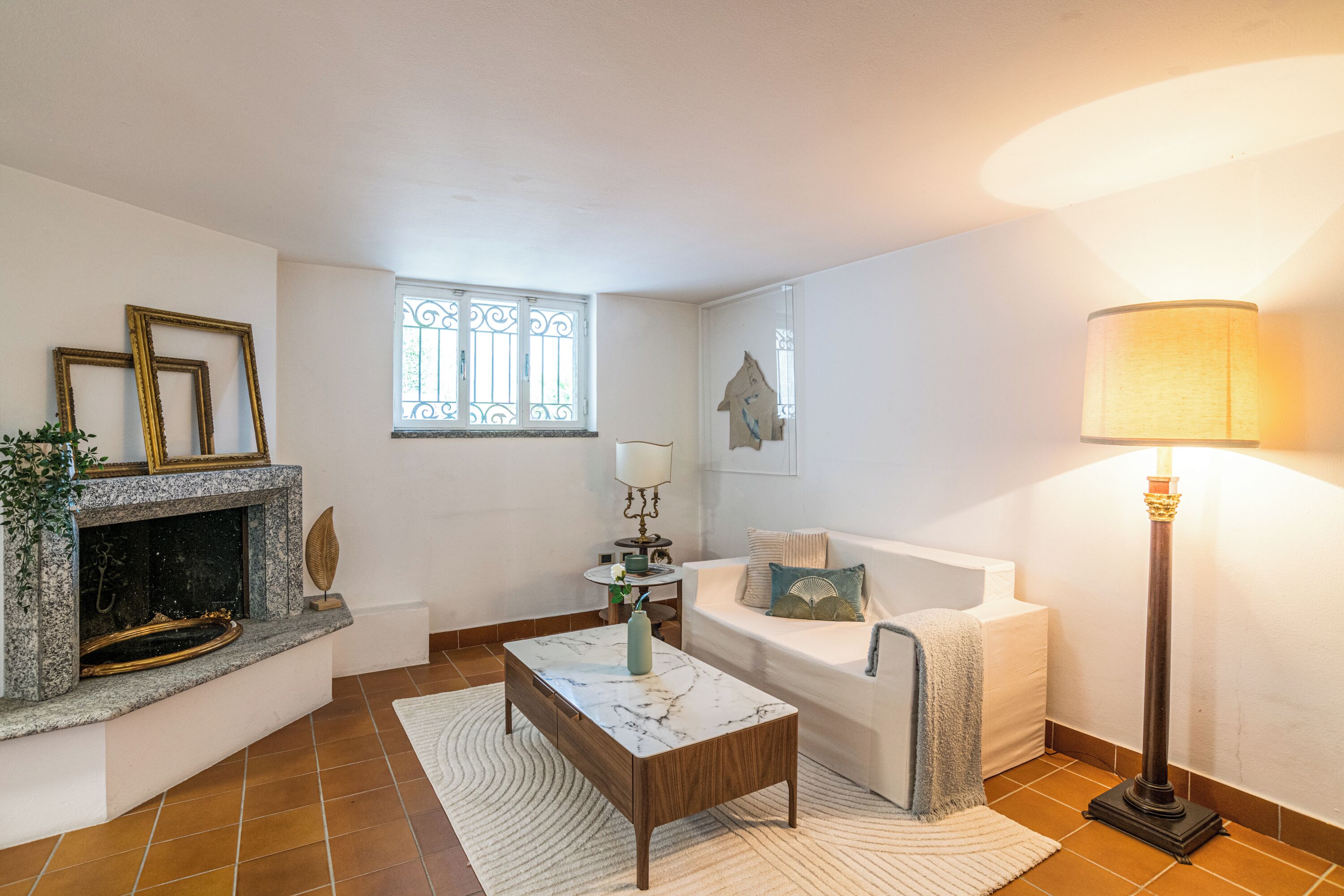 Un salon avec une cheminée, un canapé, une table basse et une lampe.