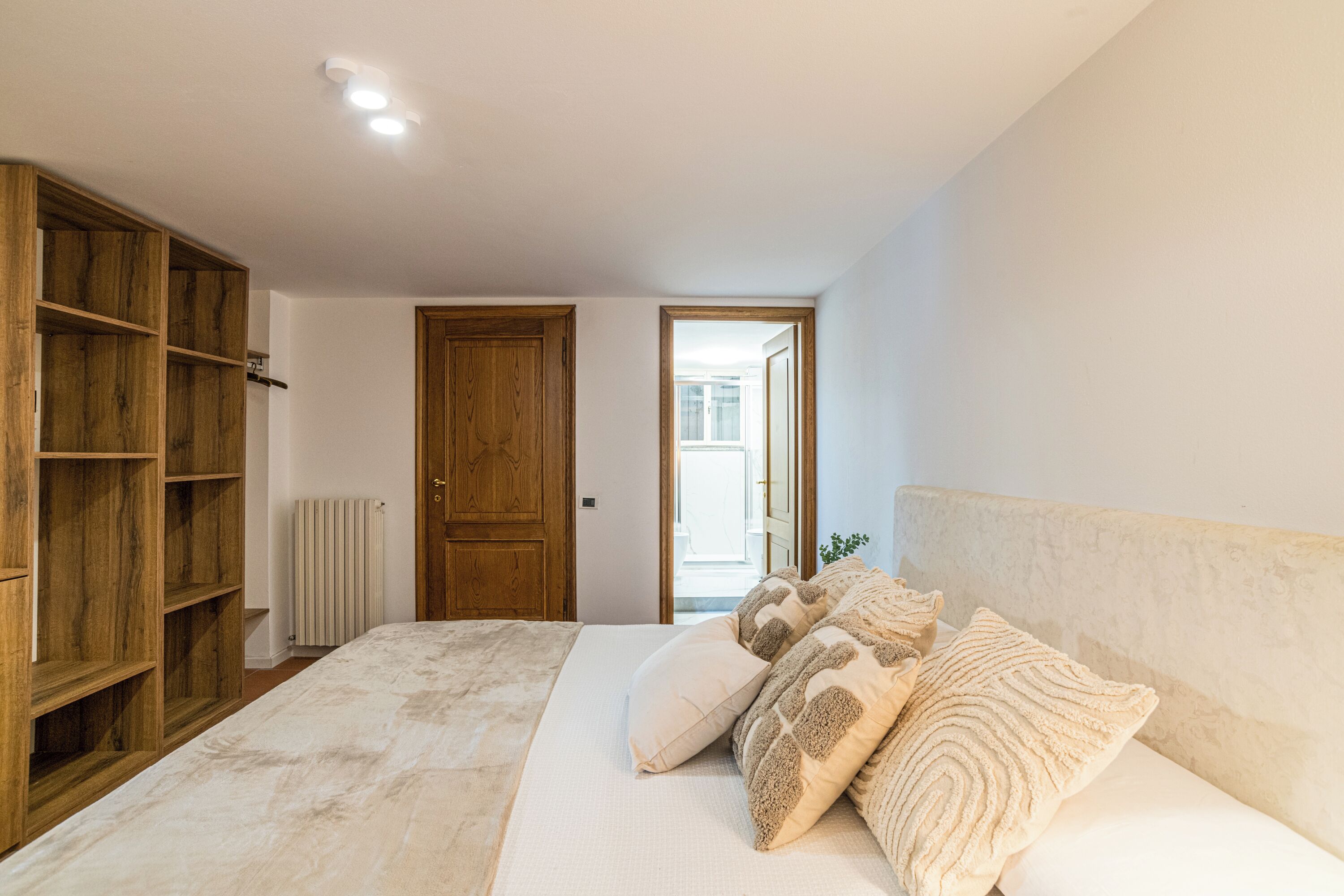 Quarto com cama grande, guarda-roupa de madeira e radiador.
