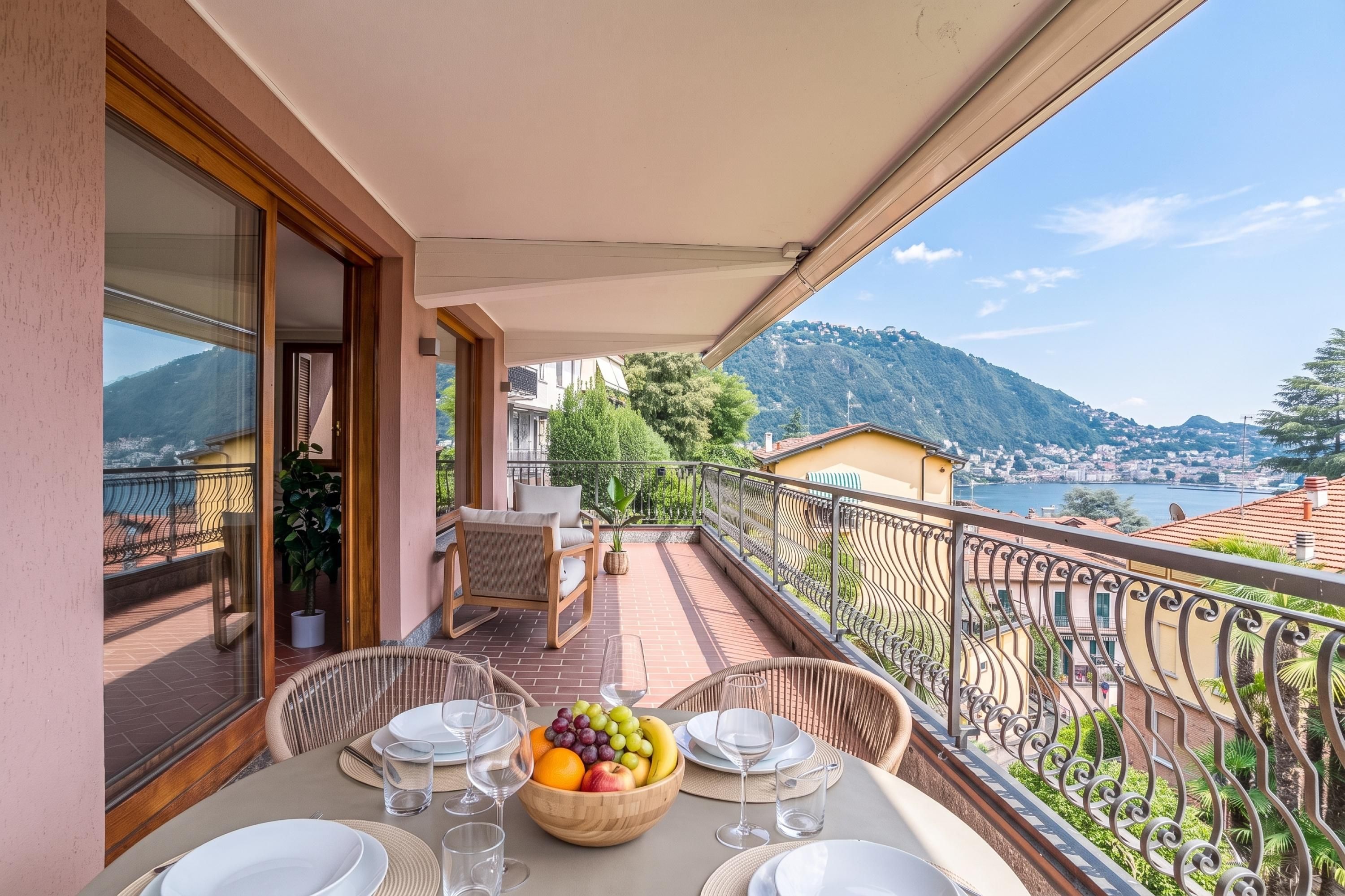 Un balcone con tavolo apparecchiato per mangiare, vista su un paesaggio montuoso.