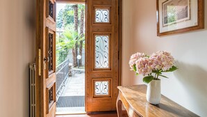 A wooden door with decorative glass panels, a white vase with pink flowers, and a framed picture on the wall. - Villa Siwaton Bellavista (Como)