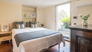 A bedroom with a large bed, a nightstand, a dresser, and a sliding glass door leading to an outdoor area. - Villa Siwaton Bellavista (Como)