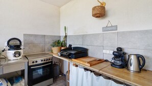 Une cuisine équipée d’une cuisinière, d’un four, d’une machine à café et d’un panier suspendu.
