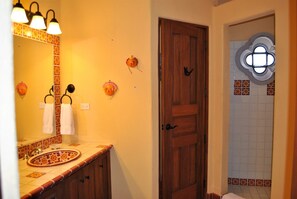 A bathroom with a wooden door, a sink with a patterned basin, and decorative wall tiles. - Stunning home with breathtaking views and steps from Community Pool (Loreto)