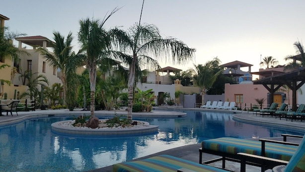 A resort pool area with lounge chairs and palm trees. - Stunning home with breathtaking views and steps from Community Pool (Loreto)