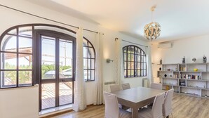 A spacious room with a large wooden table, white chairs, and a bookshelf filled with books and decorative items. - Casa Matilde Vista Mare con Piscina by Wonderful Italy (Carrozziere)