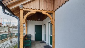A wooden building with a covered entrance, a green door, and a bench outside. - Ferienwohnung Paula (Bad Mitterndorf)