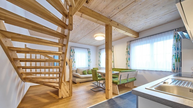 A modern kitchen with a wooden staircase, a dining area, and a sofa. - Ferienwohnung Paula (Bad Mitterndorf)