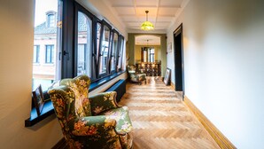 Un couloir doté d’un parquet en bois à motifs de chevrons, d’un fauteuil à motifs floraux verts et d’un banc.