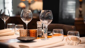 Une table à manger dressée avec des verres à vin, un chandelier et un salier et un poivrier.