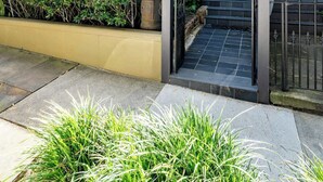 A two-story building with a balcony, a gate, and a well-maintained garden. - The Newtown Haven with Private Parking (Newtown)
