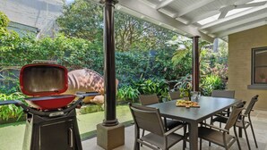 Une terrasse extérieure équipée d’un barbecue, d’une table à manger et de chaises.