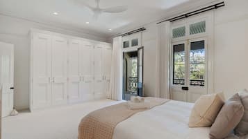 A bedroom with a large bed, a ceiling fan, and a view of the outdoors through a window.