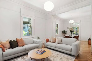 A spacious living room with two light grey sofas, a round wooden coffee table, and a large window providing natural light. - The Newtown Haven with Private Parking (Newtown)