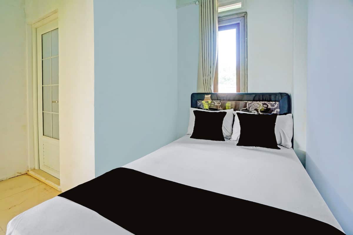 A bedroom with a bed, a window with curtains, and a door.