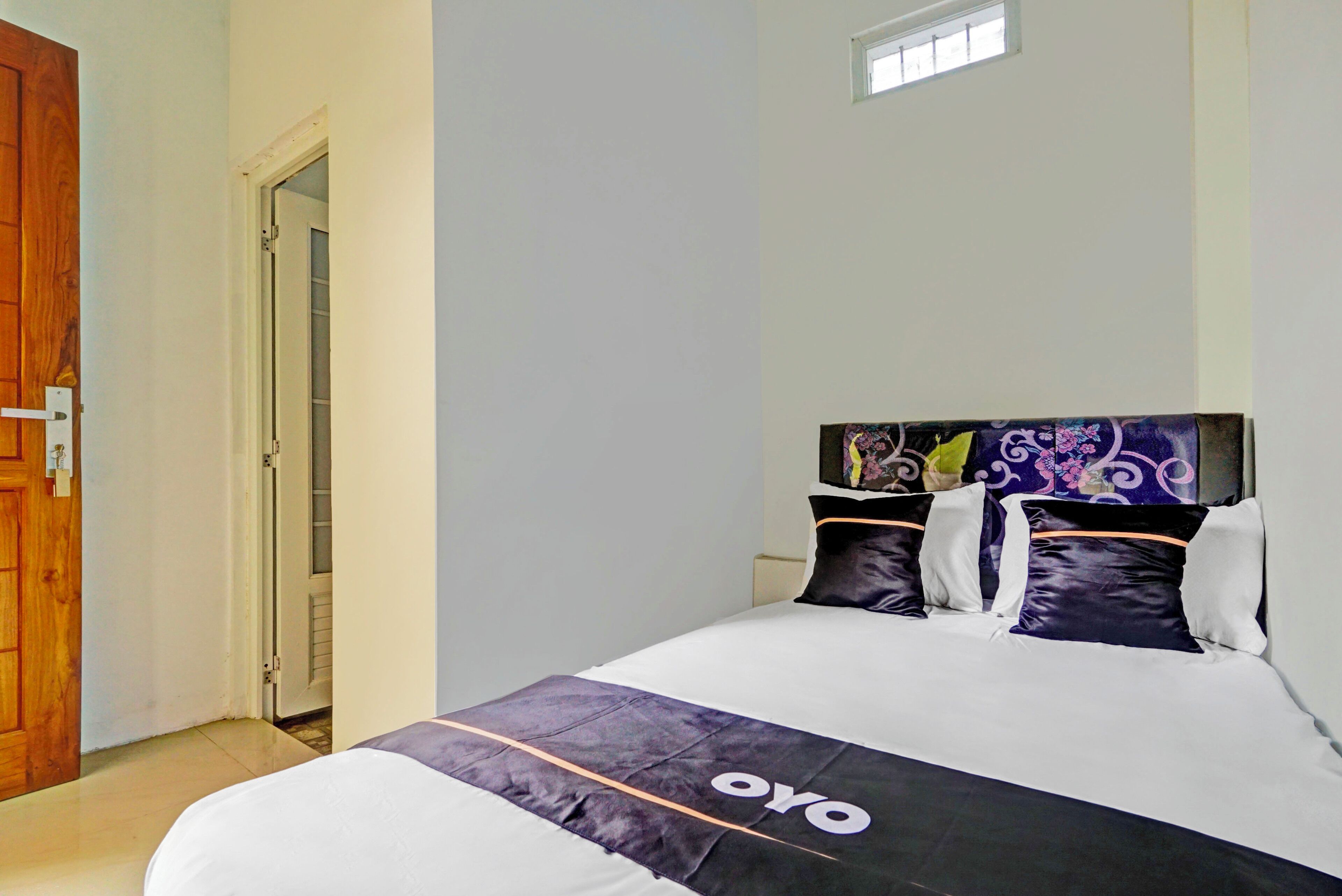 Una habitación de hotel con una cama, una puerta de madera y una ventana.